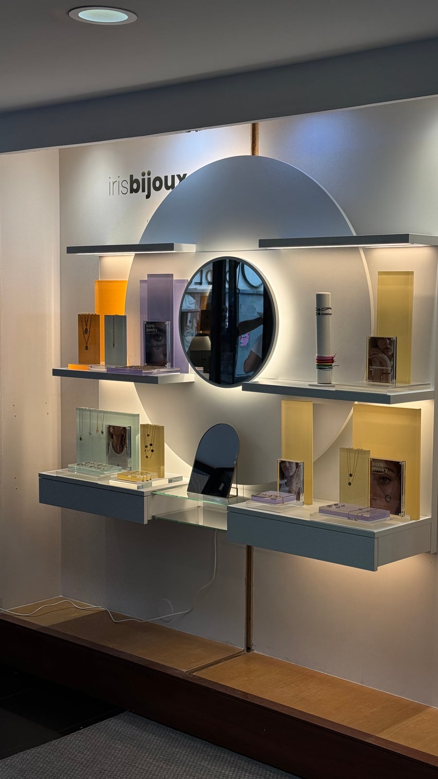 Circular backlit wall display with jewelry boxes staged on some of the shelves