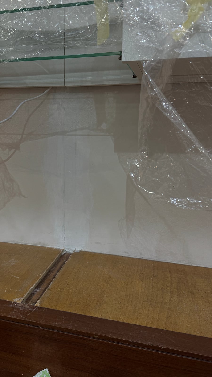Glass shelf brackets and wiring under protective wrap during the display cabinet install