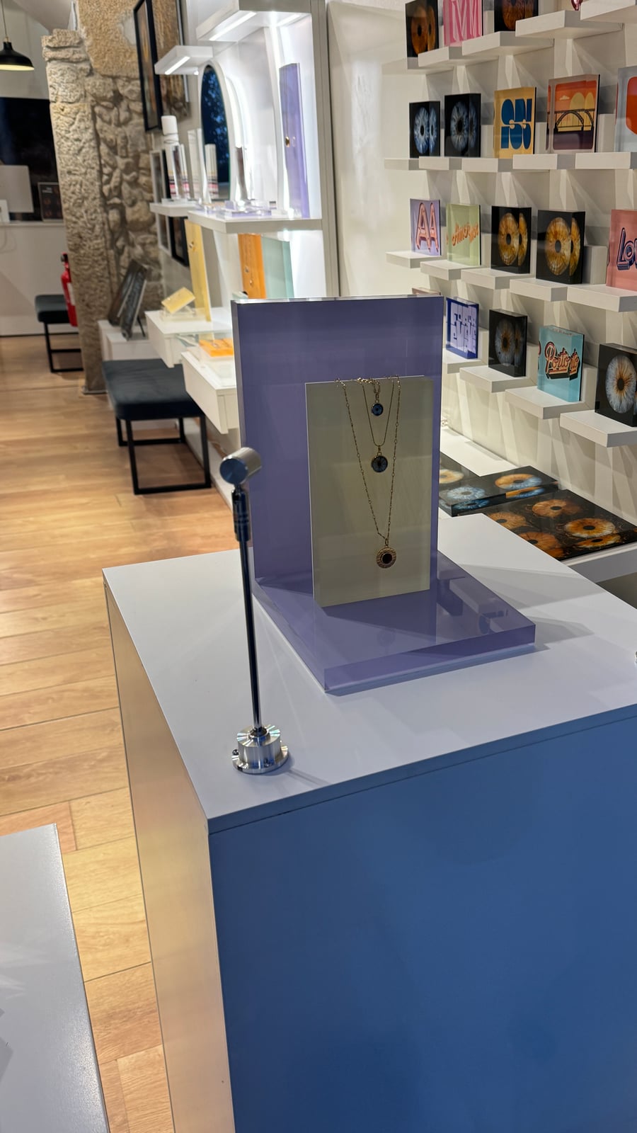 Finished LED display podium with a jewelry piece staged beside the store's exposed stone wall