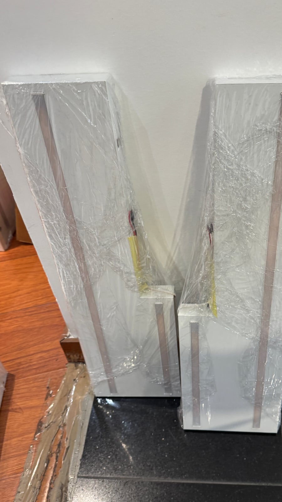 Two wrapped panel frames standing upright, wiring visible, before installation