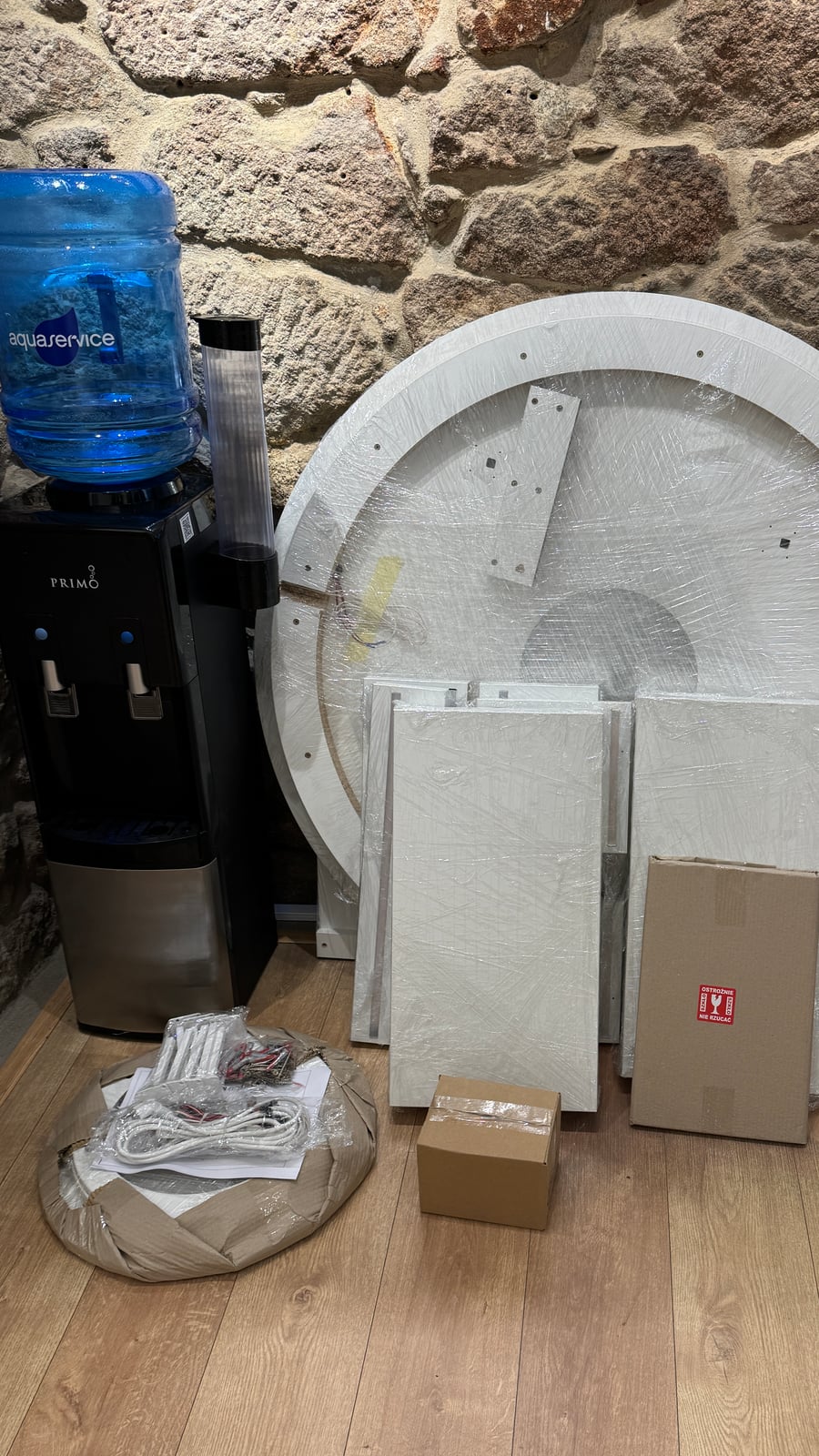 Wrapped circular panel and flat panel pieces stacked against an exposed stone wall