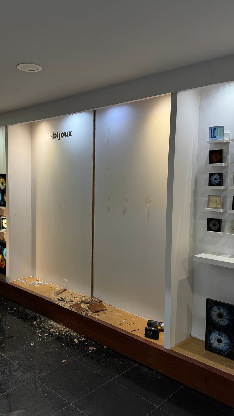 Iris Bijoux wall display partway through installation, with mounting rail and tools visible